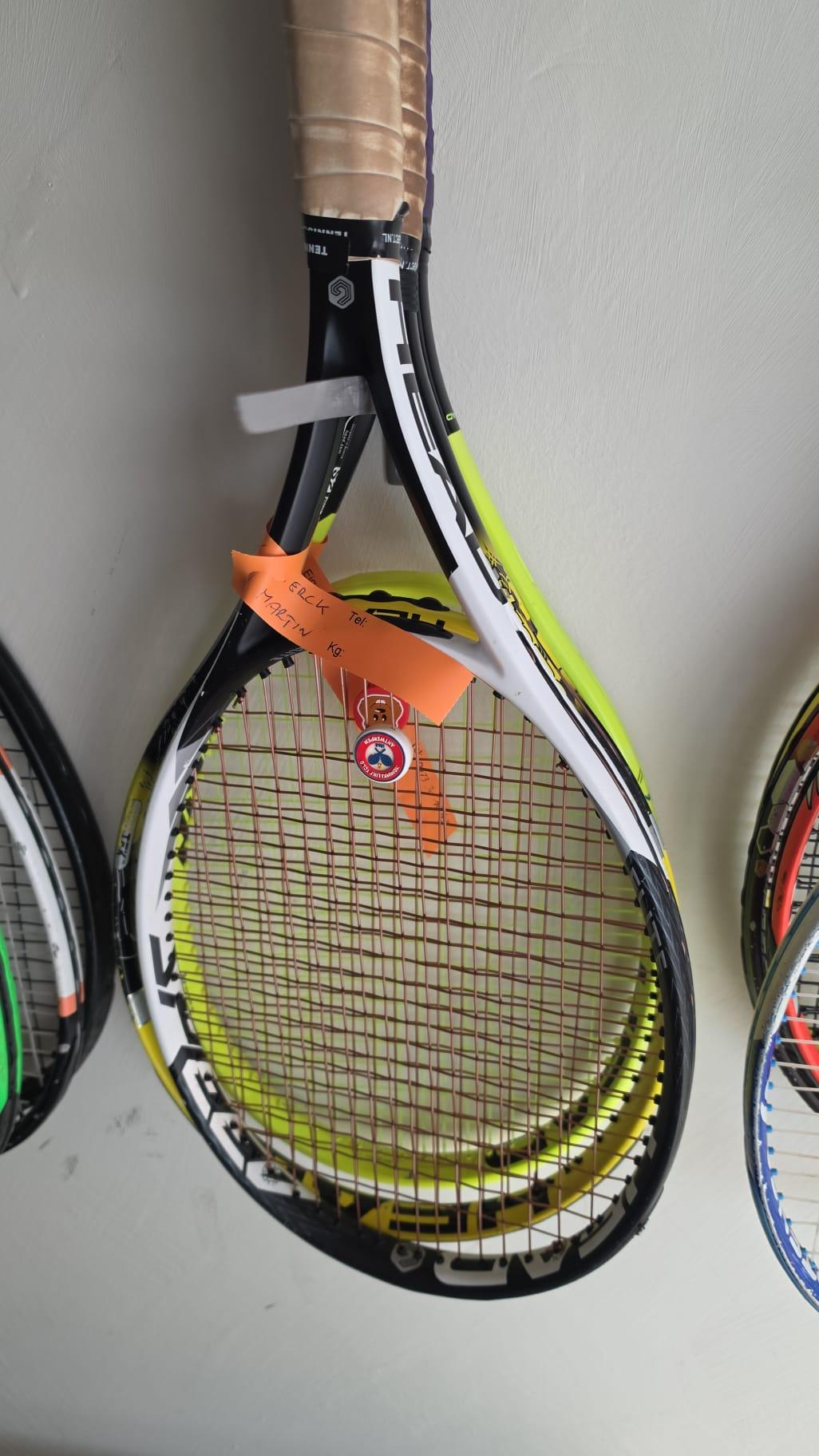 Rackets aan de haak in het clubhuis van KTCLO, met een oranje sleufetiket eraan